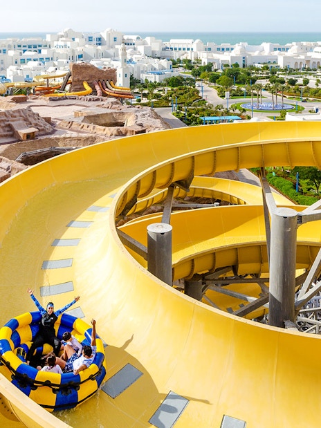 Group enjoying a yellow water slide at a theme park in Doha.