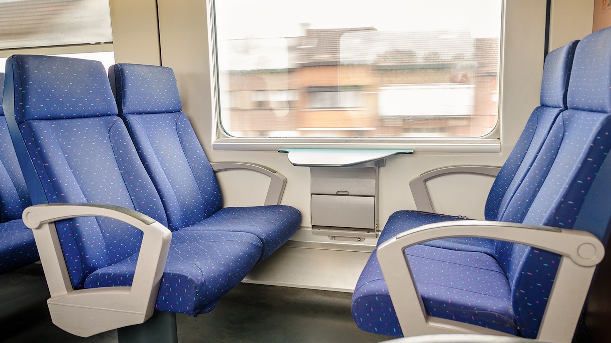 Train interior with blue seats and a window view of passing buildings.