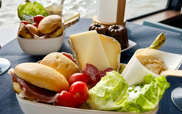 Cheese and charcuterie platter on Bateaux Bordelais Cruise with river view.