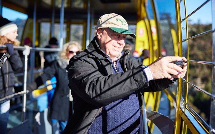 Visitor photographing views from an aerial cable car at Scenic World, Blue Mountains, Australia.