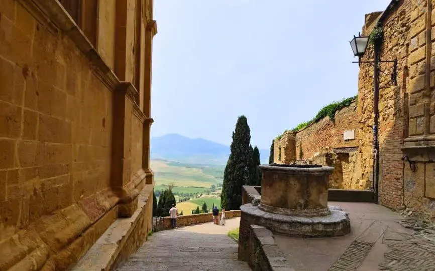 Stone pathway in Pienza with view of Val d’Orcia countryside, Tuscany.
