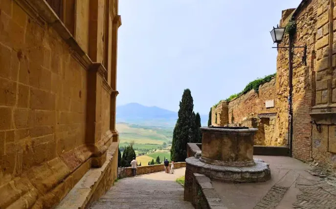Stone pathway in Pienza with view of Val d’Orcia countryside, Tuscany.
