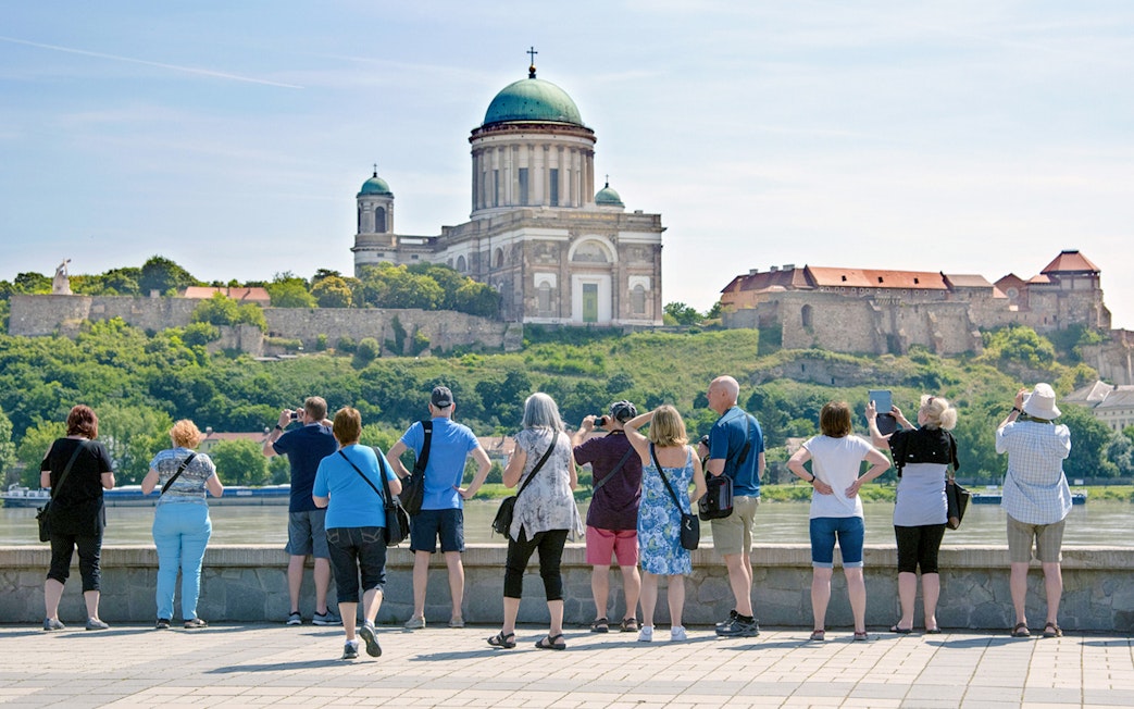Tourists photographing Esztergom Basilica from across the Danube River in Hungary.