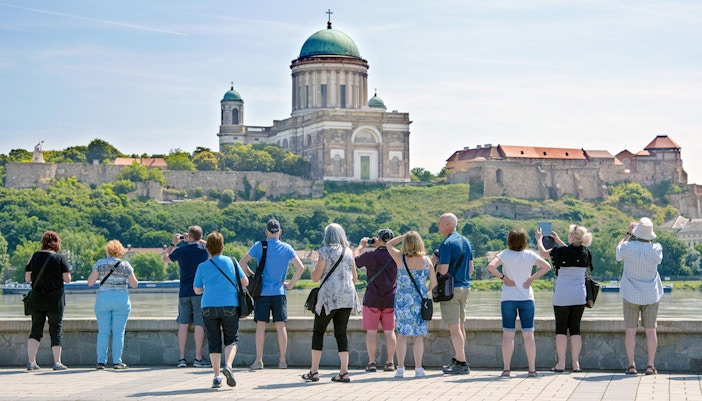 Tourists photographing Esztergom Basilica from across the Danube River in Hungary.