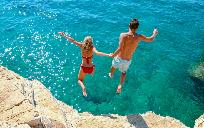 Couple cliff jumping into the Adriatic Sea, Croatia.