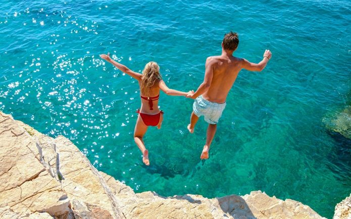 Couple cliff jumping into the Adriatic Sea, Croatia.