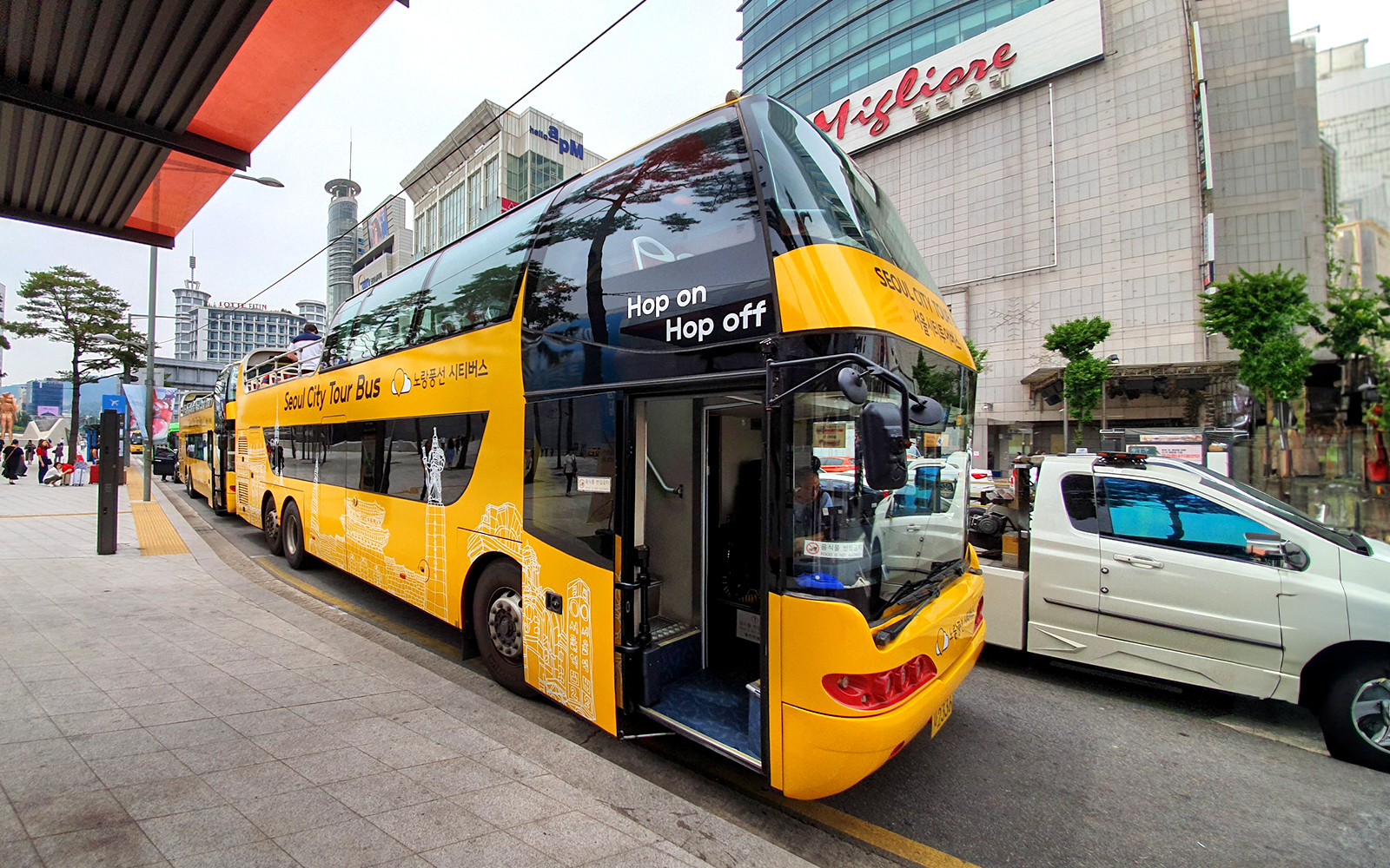 Yellow double-decker bus for Dongdaemun Hop-on Hop-off tour in Seoul city street.