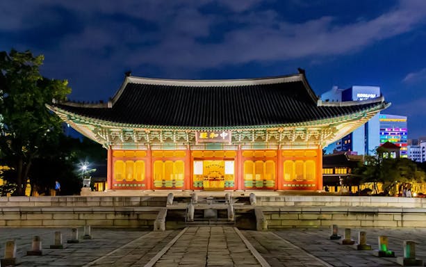 Illuminated traditional Korean building at night in Seoul during guided tour.