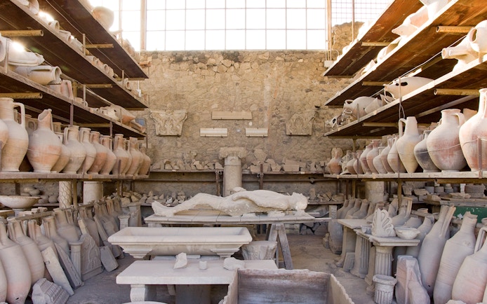 Lava cast of a person surrounded by ancient pottery in Pompeii.