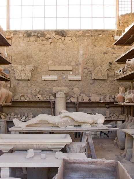 Lava cast of a person surrounded by ancient pottery in Pompeii.