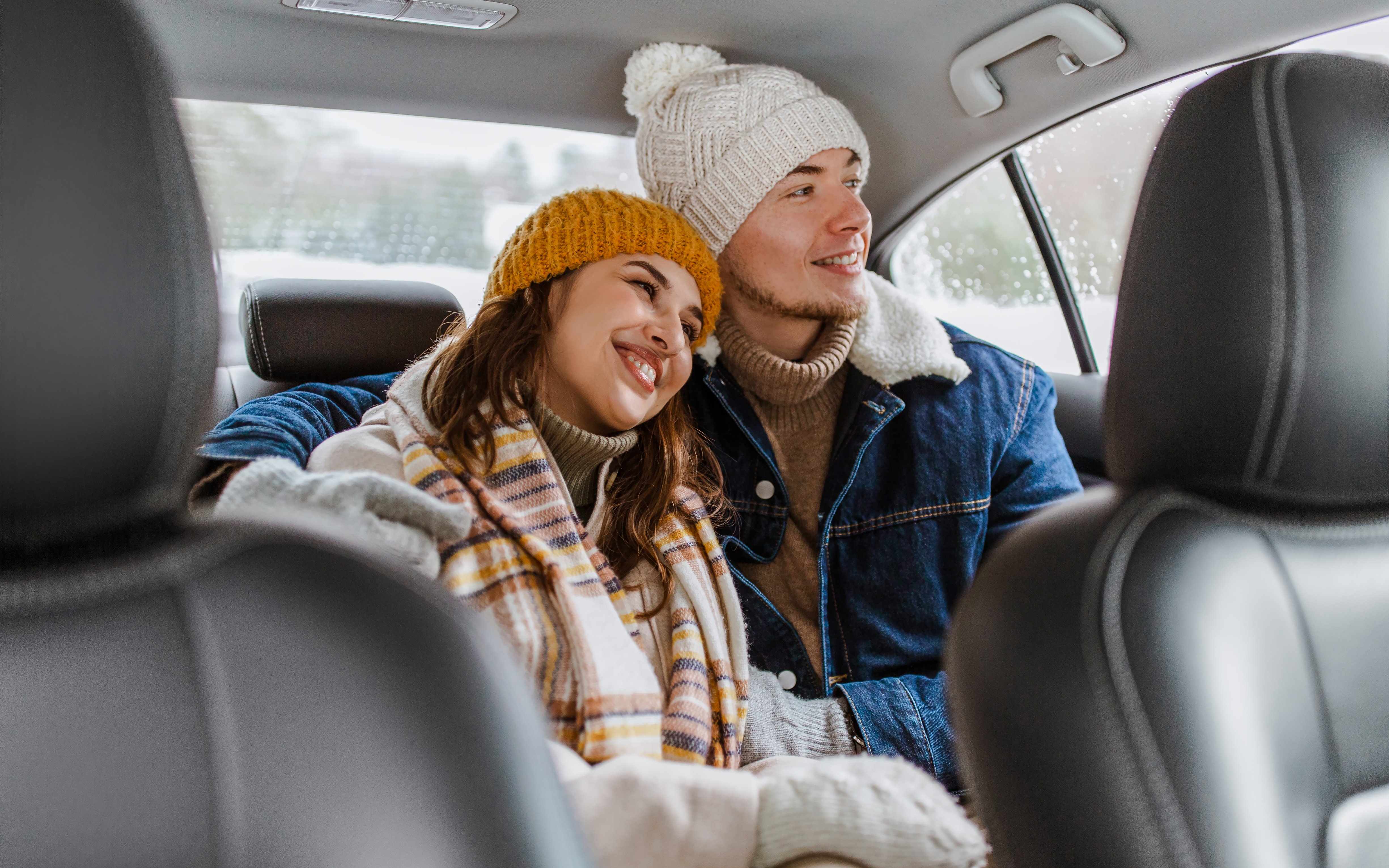 Couple in winter clothing enjoying taxi ride.