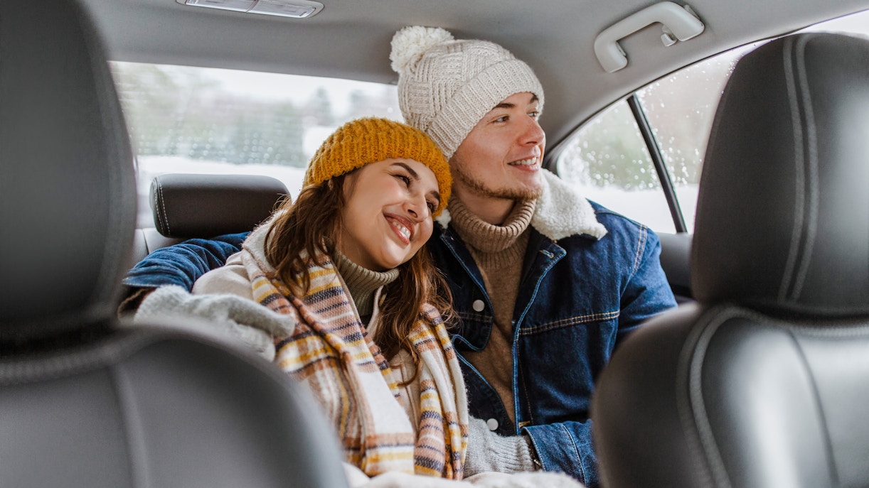 Couple in winter clothing enjoying taxi ride.