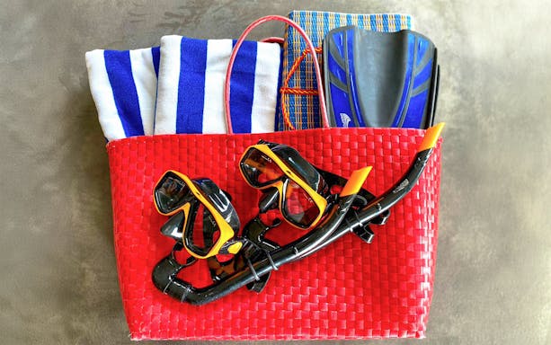Scuba gear in a red basket with towels and fins for Similan Islands tour.