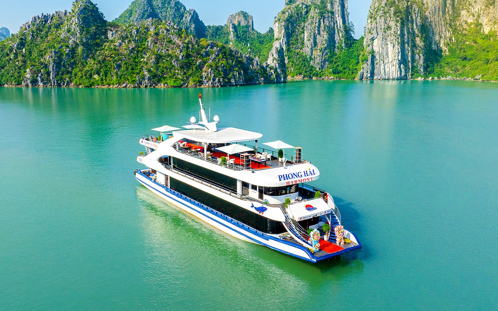 Delux Phong Hai Harmony Cruise sailing in Halong Bay with limestone karsts in the background.