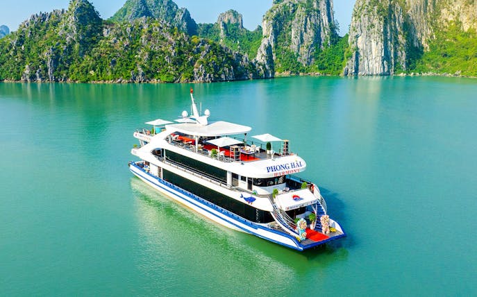 Delux Phong Hai Harmony Cruise sailing in Halong Bay with limestone karsts in the background.