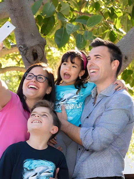Family taking selfie near colorful parrots at Marineland Mallorca aviary.