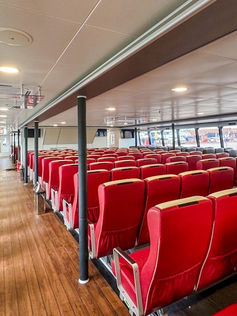 Ferry interior with rows of red and brown seats, Singapore to Bintan route.