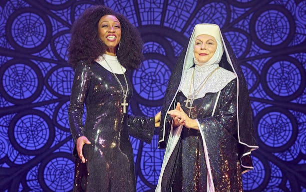 Two performers in sequined costumes from the musical Sister Act on stage.