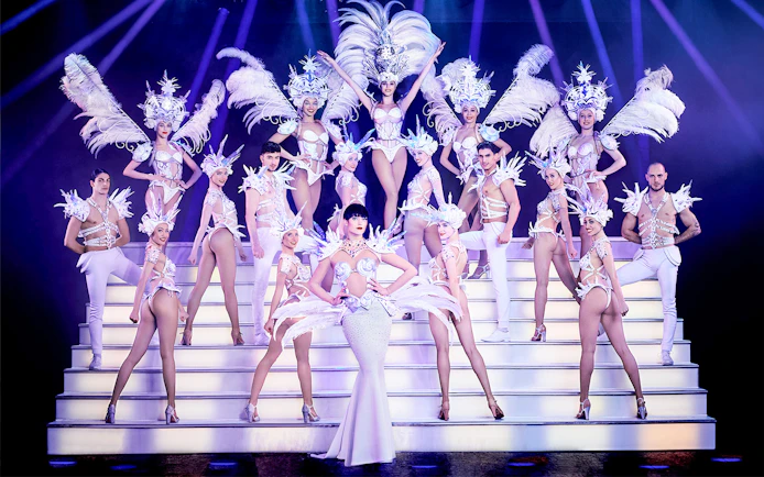 Performers in elaborate costumes on stage at Paradis Latin Christmas Eve show.