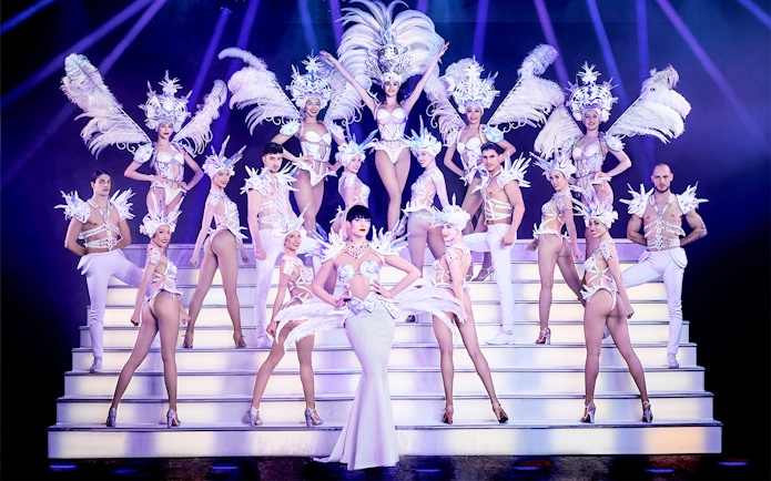 Performers in elaborate costumes on stage at Paradis Latin Christmas Eve show.