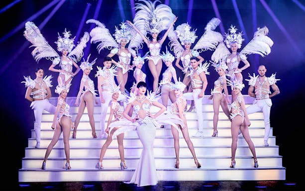 Performers in elaborate costumes on stage at Paradis Latin Christmas Eve show.