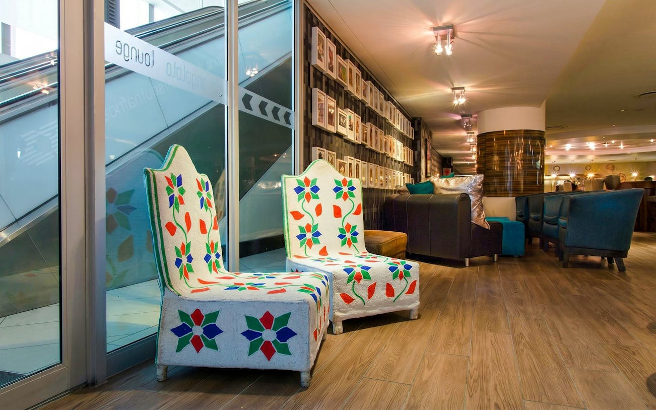 Shongololo Lounge seating area with colorful chairs at O. R. Tambo International Airport Terminal A, Johannesburg.