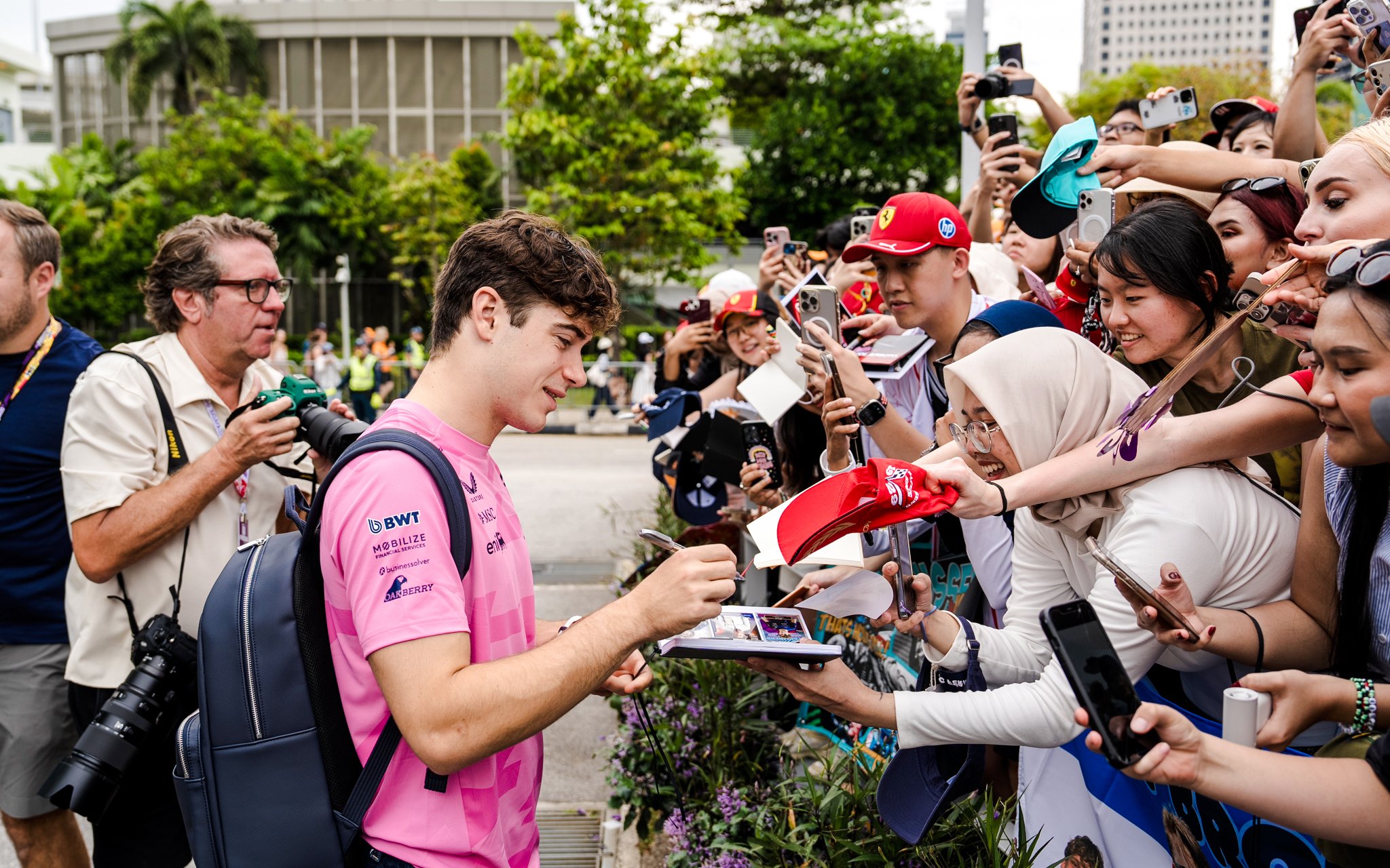 Race car driver signing autographs for fans at a public event.