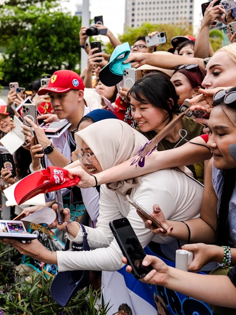 Race car driver signing autographs for fans at a public event.