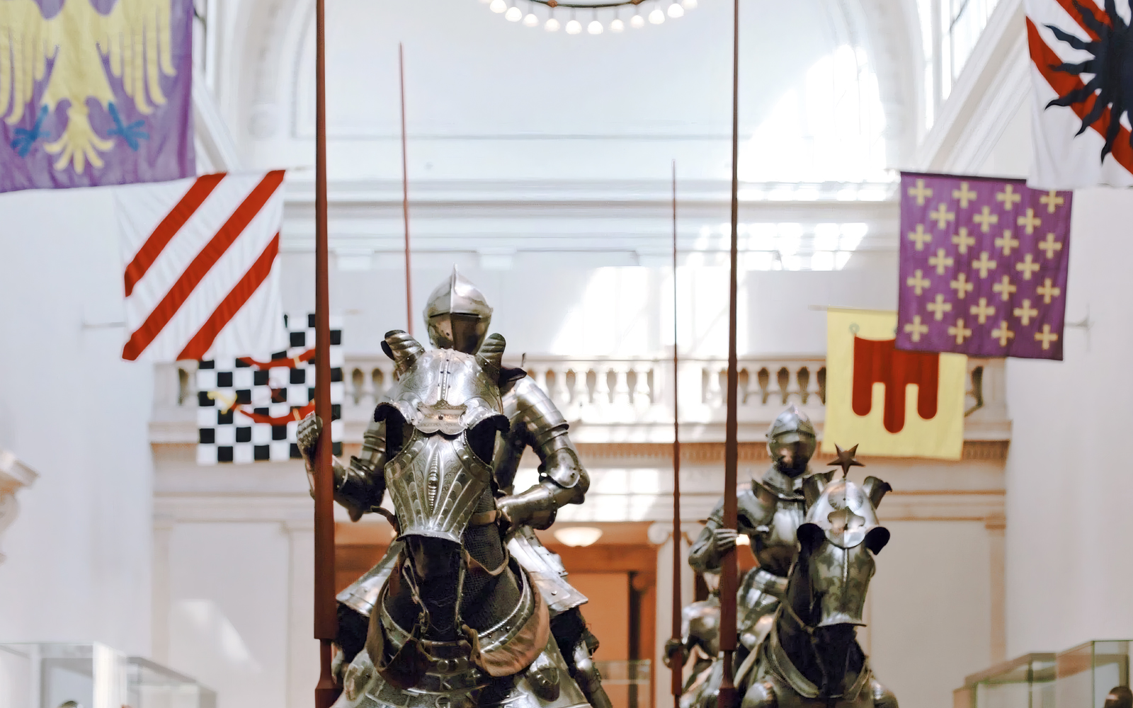 Three suits of 16th-century German field armor for knights on horseback displayed in a museum.