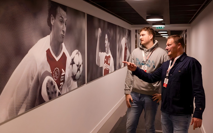 Visitors admire football player photos at Johan Cruijff ArenA Classic Tour.