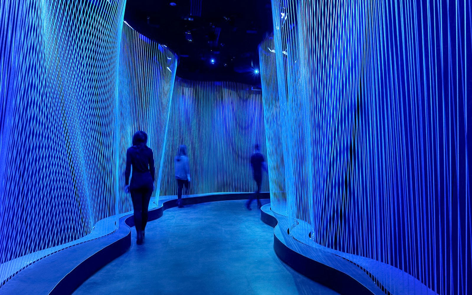 Visitors walking through illuminated blue corridor at Museum of the Bible.