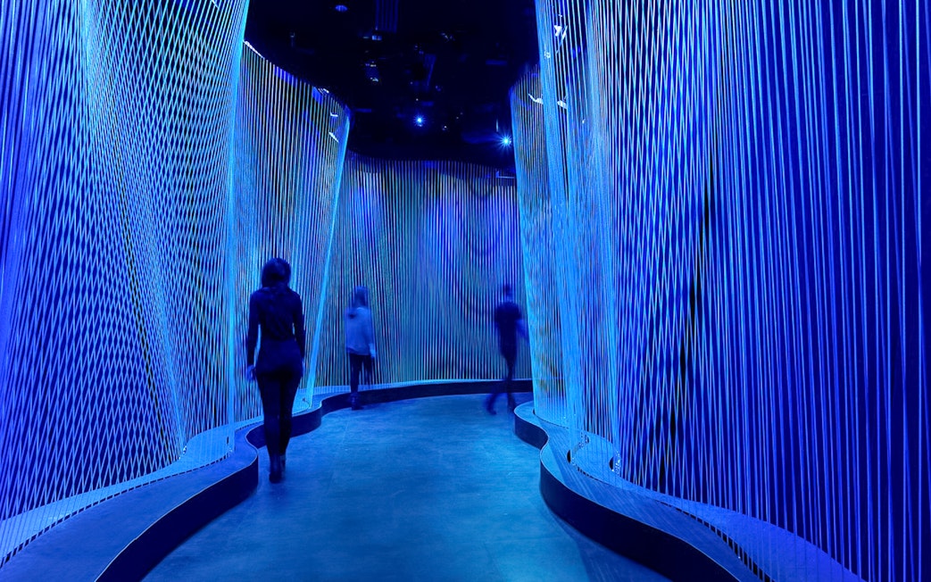 Visitors walking through illuminated blue corridor at Museum of the Bible.