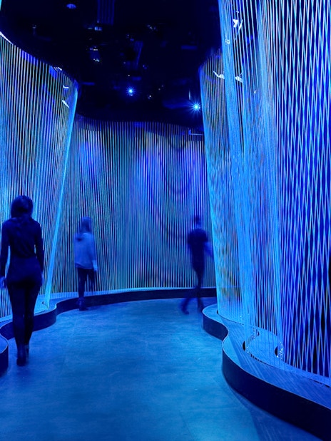 Visitors walking through illuminated blue corridor at Museum of the Bible.