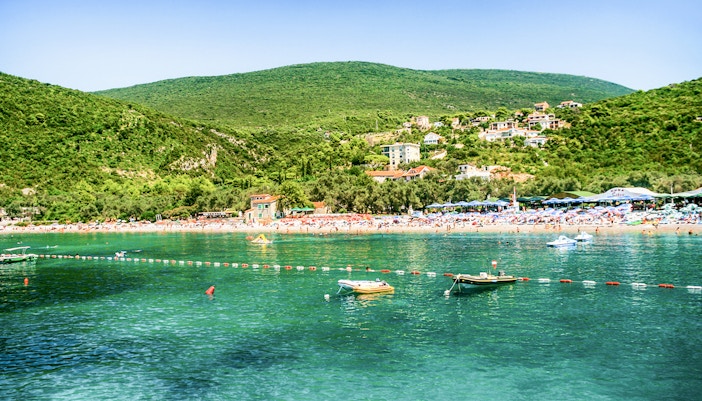 Zanjic Beach in Montenegro with clear blue waters and surrounding lush greenery.