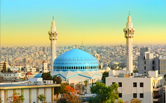 Blue-domed King Abdullah I Mosque with minarets in Amman cityscape, Amman City Sightseeing Tour.