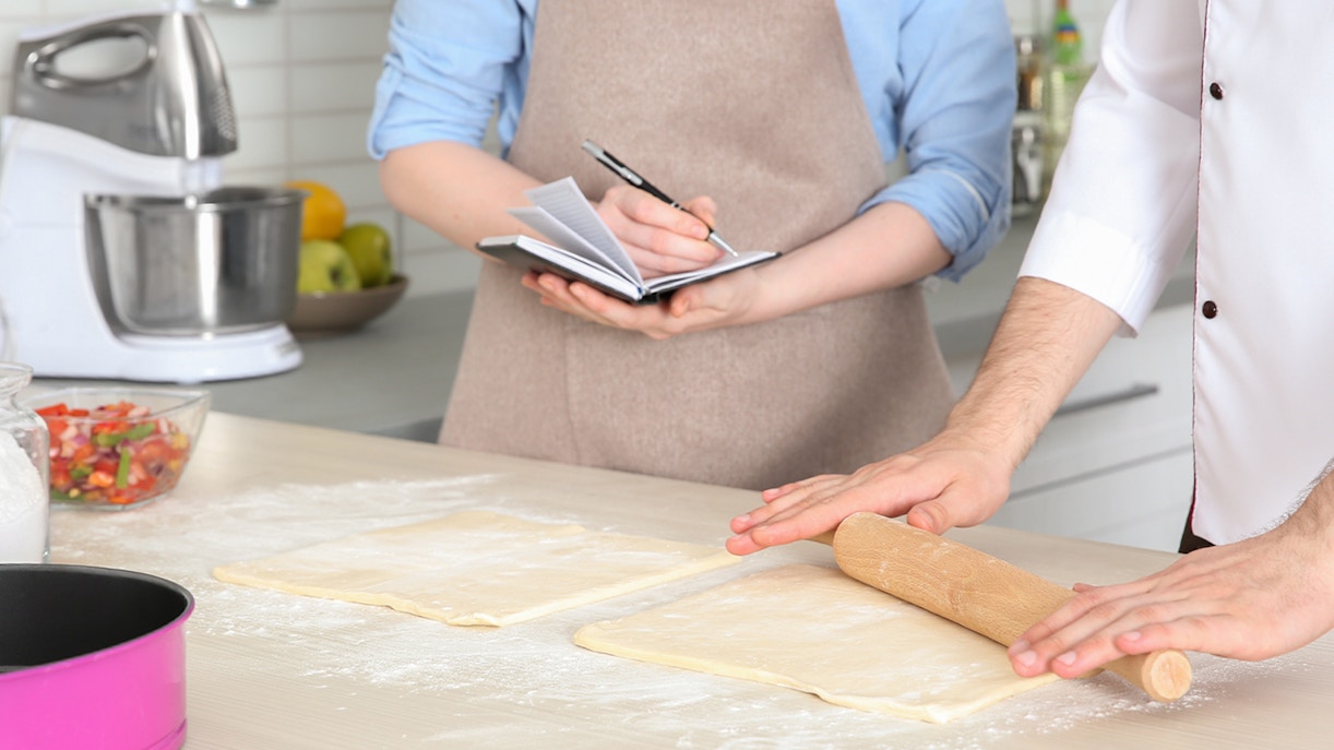 Person taking notes during a cooking class in a kitchen setting.