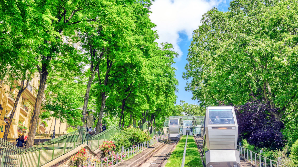 Montmartre funicular ascending through lush green trees in Paris.