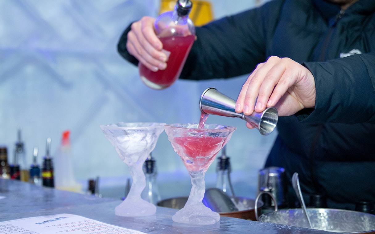 Bartender pouring red cocktail into ice glasses at IceBar Surfers Paradise.