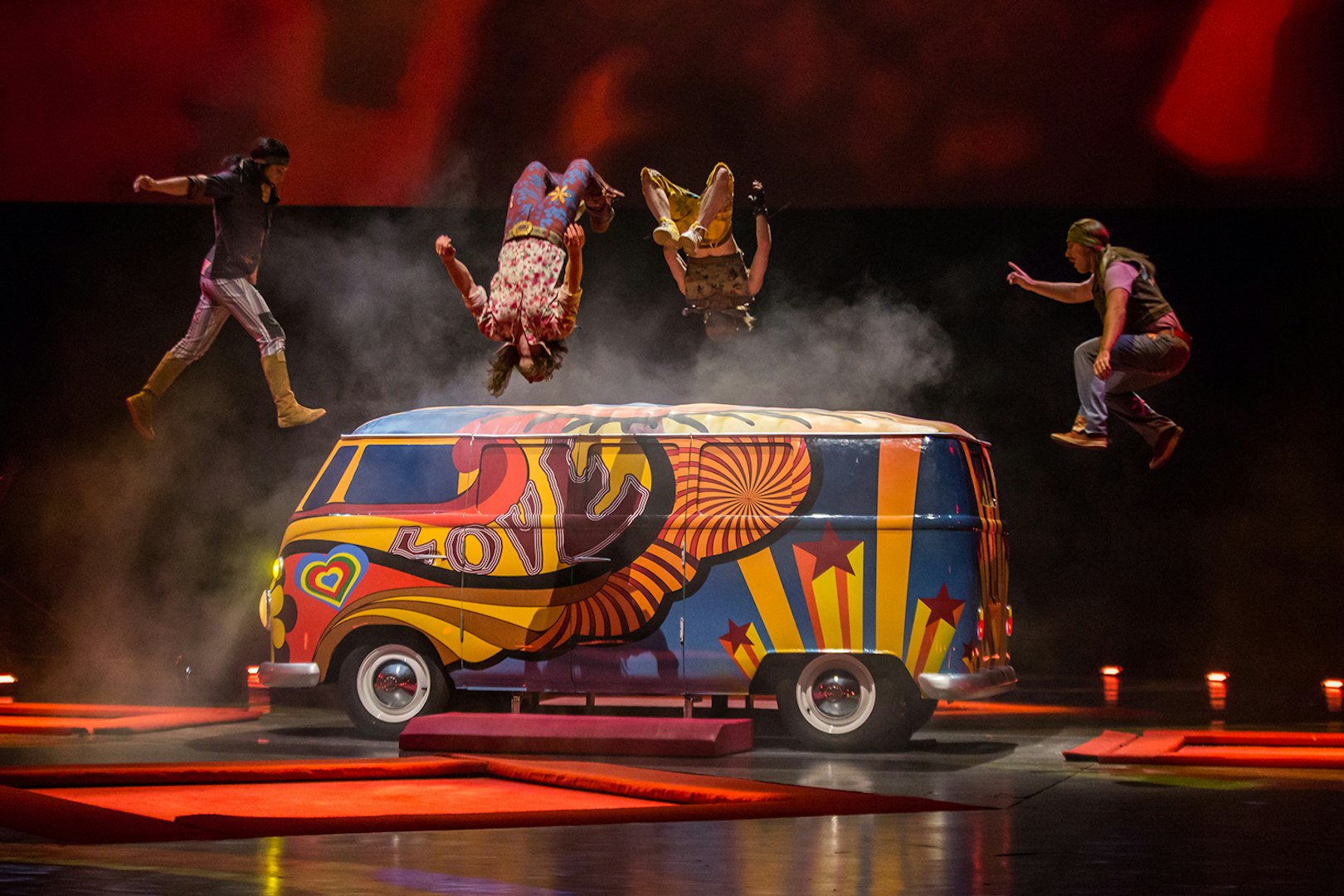 Performers doing acrobatics over a colorful van at The Beatles LOVE show.