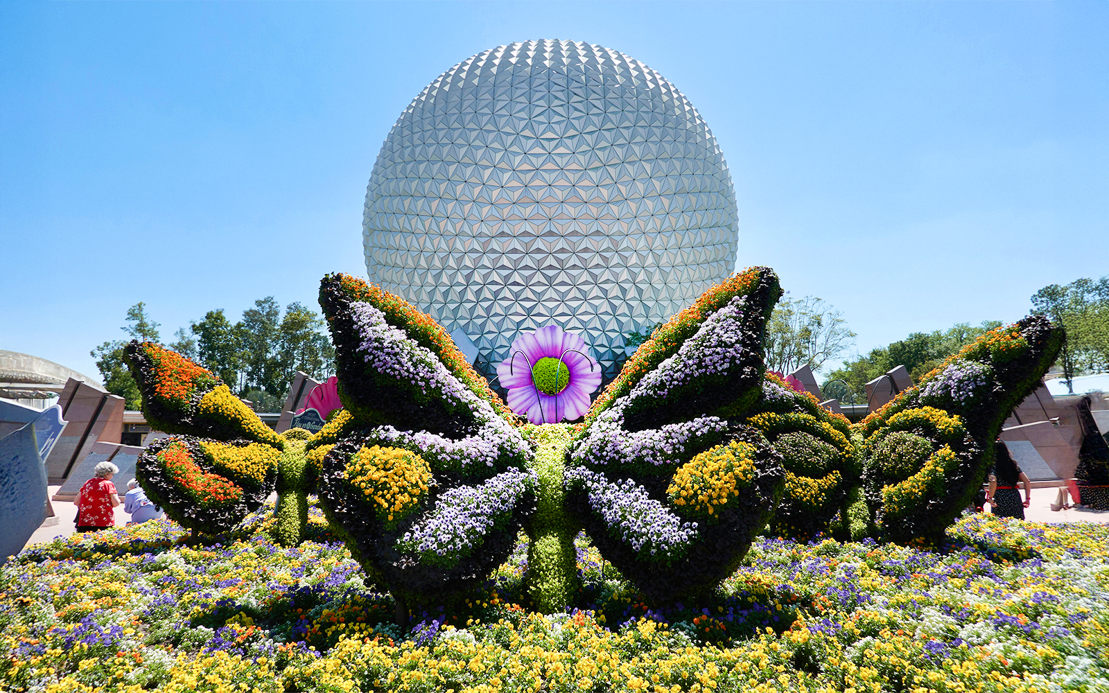 Topiary butterfly in flower garden at EPCOT, Bay Lake, Florida with geodesic sphere in background.