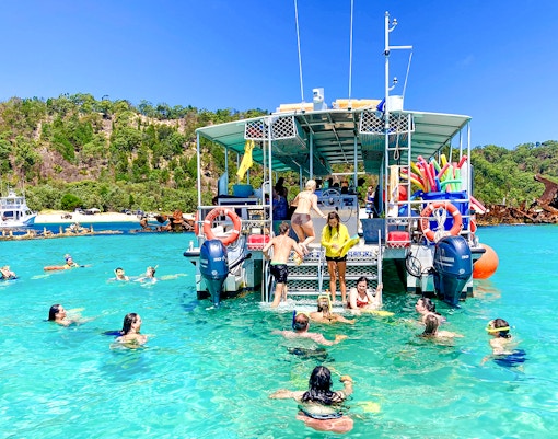 People swimming and snorkeling near a boat