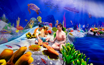 Children exploring vibrant coral reef at Curiosity Cove Wetlands Reef Retreat.