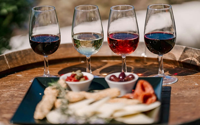 Glasses of wine and appetizers on a barrel during Akrotiri Excavations and Red Beach tour.
