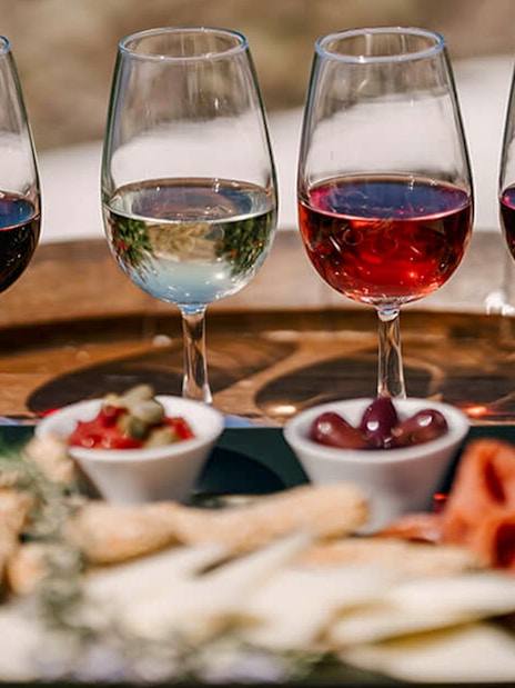 Glasses of wine and appetizers on a barrel during Akrotiri Excavations and Red Beach tour.
