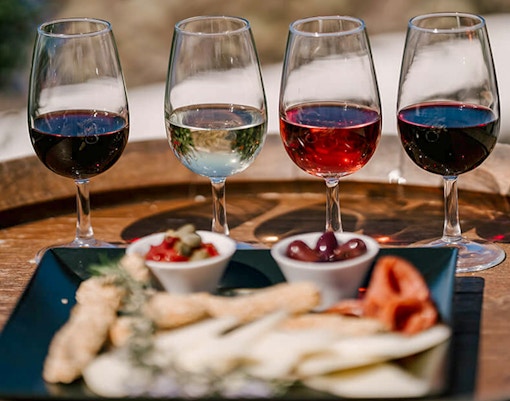 Glasses of wine and appetizers on a barrel during Akrotiri Excavations and Red Beach tour.