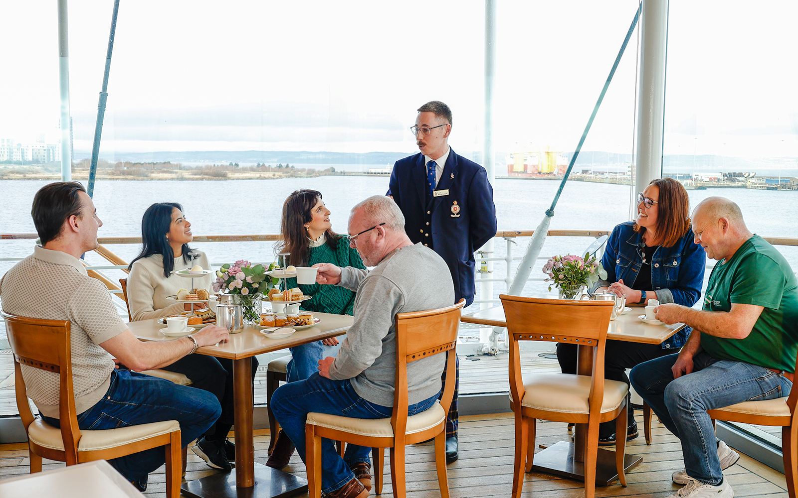 Guests enjoying afternoon tea on the Royal Yacht Britannia with a guide.