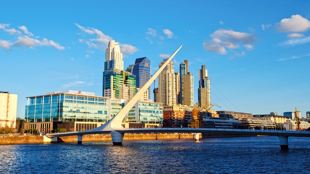 Puente de la Mujer bridge over water with Buenos Aires skyline in the background.