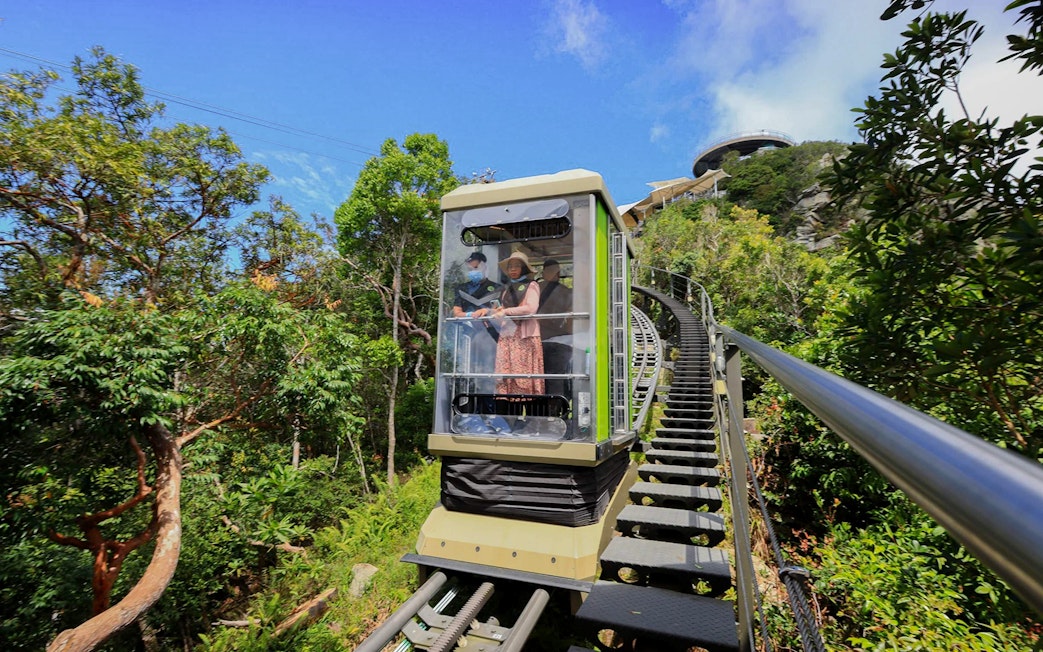 Tourist riding SkyGlide through lush forest in Langkawi.