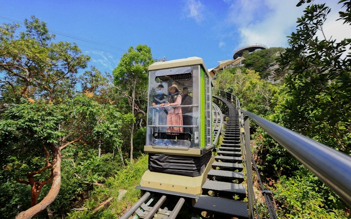 Tourist riding SkyGlide through lush forest in Langkawi.