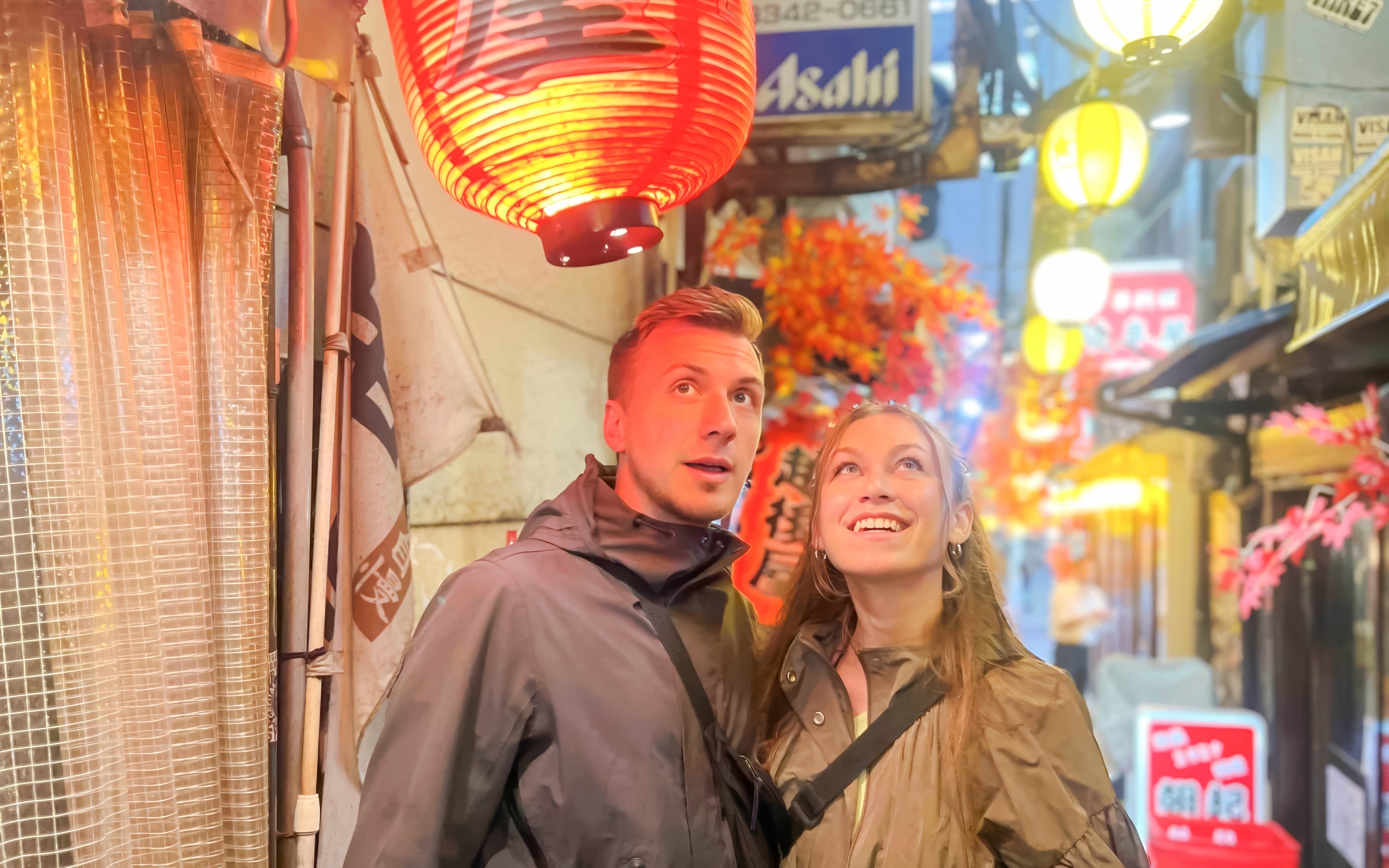 Couple admiring lanterns in Shinjuku alley during Tokyo food tour.